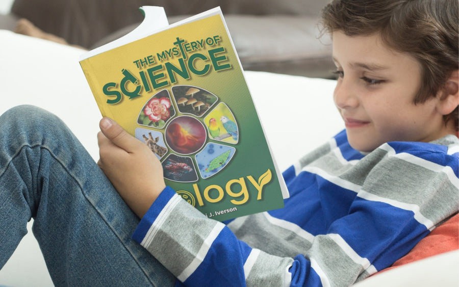 A boy reads The Mystery of Science Biology book on a sofa.