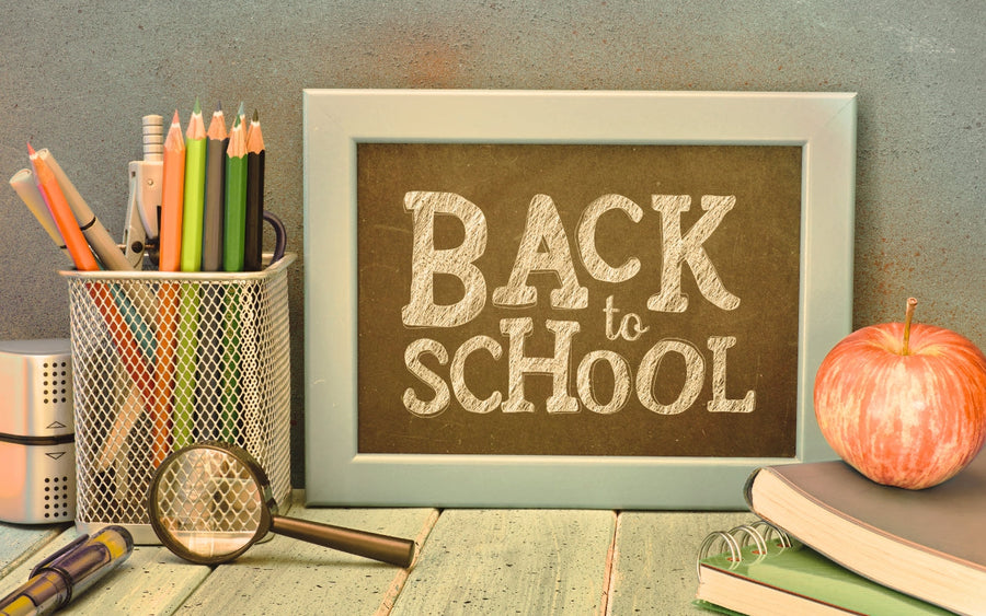 Back to School sign beside pencils, notebooks, and an apple.